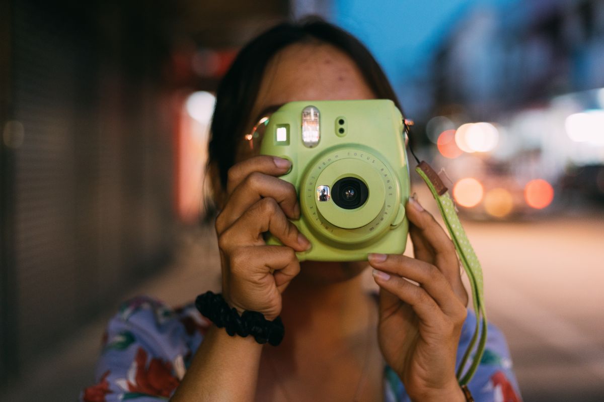 Detail ženy pri fotení instantným fotoaparátom.