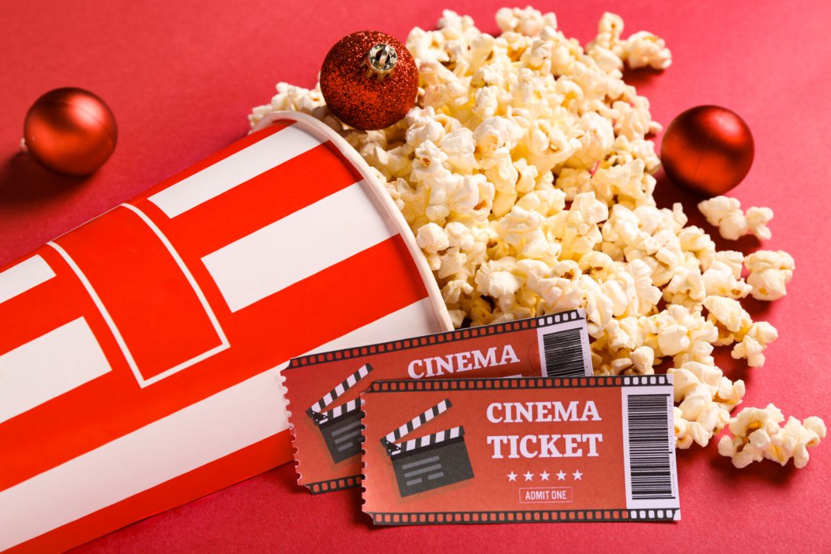 Popcorn a lístky do kina na červenom pozadí.