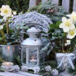 Adventné dekorácie s kvetinami v plechových kvetináčoch na drevenej lavičke.