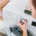 Detail ženy nastavujúcej program na práčke.