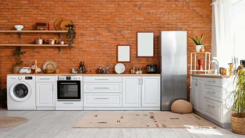 Moderná biela kuchyňa so spotrebičmi a tehlovou stenou.