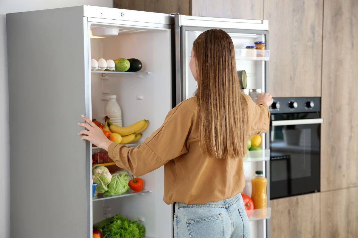 Mladá žena stojí pri otvorenej chladničke.