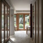 Chodba s presklenou stenou a knižnicou, vedúca do dennej jedálne a obývačky.