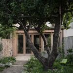 Drevená prístavba s presklenými dverami pri zadnom dvore s jabloňou.