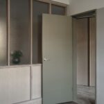 Olivovozelené dvere vedľa steny s presklením v minimalistickom interiéri.