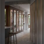 Chodba s tehlovou podlahou a drevenými dverami pod betónovým stropom.