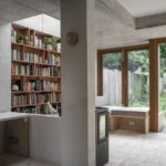 Terakotová knižnica pod svetlíkom vedľa čiernej pece a betónového stĺpa.