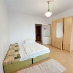 Staršia spálňa s dvoma spojenými posteľami v zelenej farbe, staršou skriňou a drevenou podlahou.