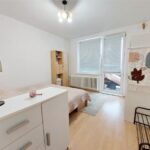 Pôvodná detská izba s bielou komodou, drevenou posteľou, oknom so žalúziami a nástennou tapetou.