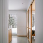 Svetlá vstupná chodba so sivou podlahou a posuvnou drevenou stenou s matným presklením.