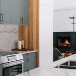 Sivá kuchynská linka s mramorovou zástenou, antikorová rúra a drevený vertikálny obklad steny.