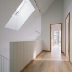 Presvetlená chodba s drevenou podlahou a otvorenými dverami do miestostí.