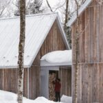 Zasnežená strieška medzi dvoma domami s drevenou fasádou