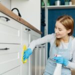 Mladá žena pri utieraní dvierok na kuchynskej linke.