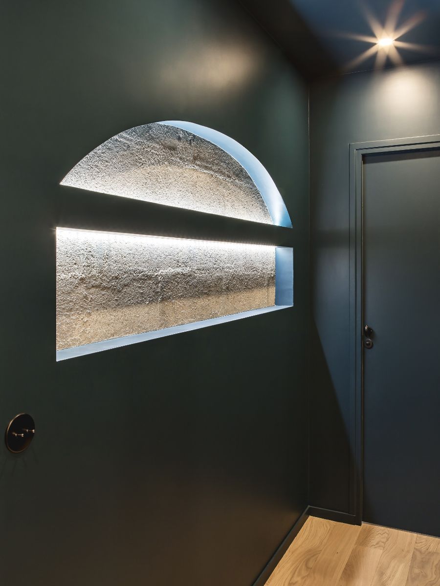 Všimnite si, ako netradične je riešená nika pri vchode. Okrem toho, že výklenok môže fungovať ako polica, zároveň odhaľuje surovú stenu za panelom.