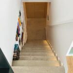 Betónové schodisko s bodovým osvetlením stupňov vedľa bielej knižnice.