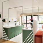 Kuchynská zóna so zelenými skrinkami, bielou kovovou konštrukciou a jedálenským kútom s lavičkou.