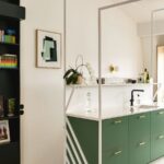 Zelená kuchynská linka s bielou kamennou doskou a čiernou vodovodnou batériou.