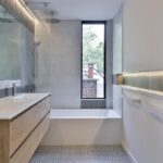 Umývadlo s dubovou skrinkou v kúpeľni s vaňou spojenou so sprchovým kútom a podsvietenými skrinkami.