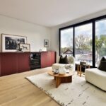 Oddychová miestnosť s bordovou skrinkovou zostavou, zabudovanou vinotékou, kreslami a vstupom na balkón.