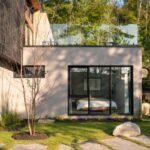 Časť moderného domu s veľkoformátovým presklením v lesnom prostredí.