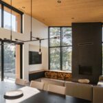 Obývacia izba s čiernym krbom, dreveným stropom, béžovou sedačkou a veľkoformátovými presklenými stenami.