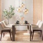 Sklenený jedálenský stôl, béžové čalúnené kreslá, tri sklenené lustre a vysoký zelený fikus.