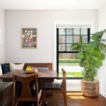 Drevený rohový kút, stôl z tmavého masívu, čierne kožené stoličky a veľký fikus v prútenom koši.