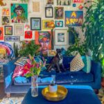 Interiér s množstvom farebných obrazov, sýtomodrou pohovkou, rastlinami a farebnými vankúšmi.