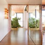 Svetlá chodba s drevenými parketami, zrkadlovou vstavanou skriňou a farebným skleneným svietidlom na stene.