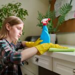 Žena utiera prach handrou a prípravkom v spreji.