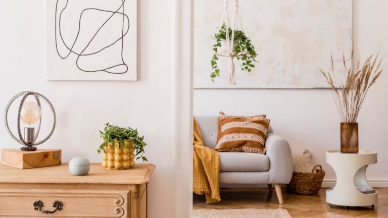 Drevená retro komoda s dizajnovou stolnou lampou, zelenou rastlinou v žltom kvetináči a abstraktným lineárnym obrazom.