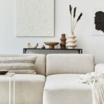 Moderná obývacia izba s béžovou sedačkou a stolíkom s rozličnými vázami a dekoráciami.