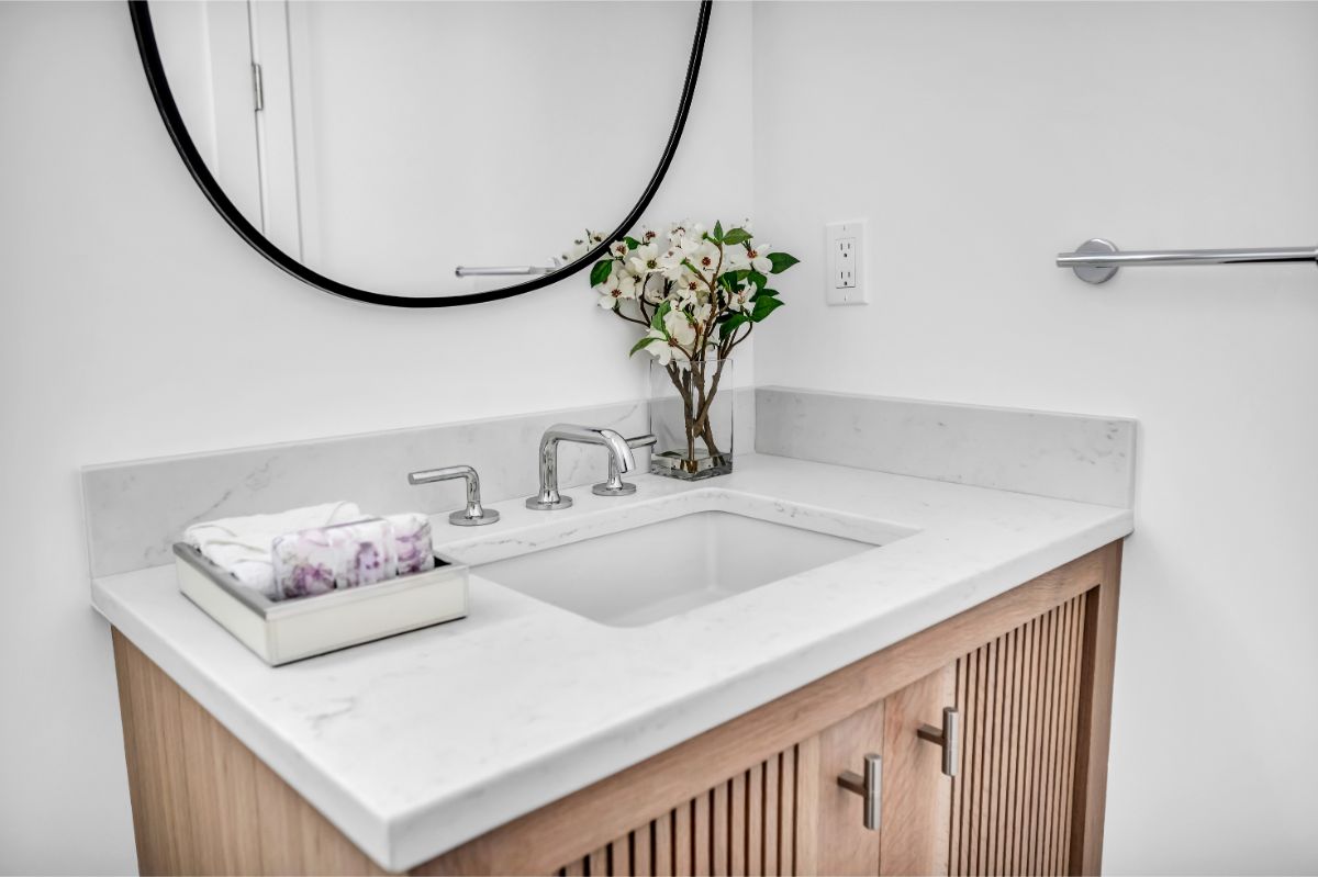 Skrinka v kúpeľni so zapusteným umývadlom a doskou z kremeňa.