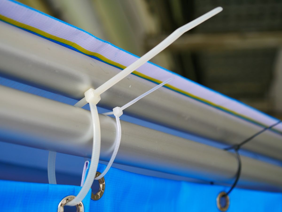 Detail na kryciu plachtu, zaistenú o kovovú konštrukciu sťahovacou páskou.