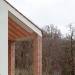 Exteriérový stĺp terasu z červenej tehly pri bielej fasáde domu.