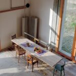 Drevený jedálenský stôl s rôznymi drevenými stoličkami v interiéri domu s drevenou podlahou.