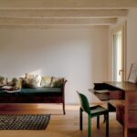 Tmavozelená čalúnená pohovka a starožitný písací stôl v interiéri