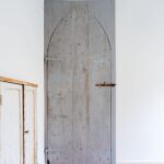 taré sivé drevené dvere s oblúkovým výrezom a kovovou západkou.