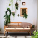 Interiér s ratanovou sedačkou pri veľkom okne, izbovými rastlinami a zelenými dekoráciami na stene.