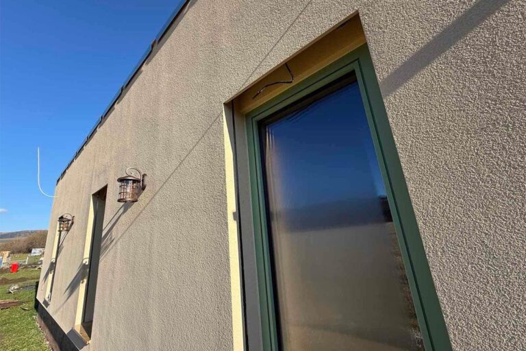 Fasáda jednopodlažného domu s vysokými oknami v príprave na vonkajšie žalúzie.