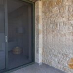 Posuvné vstupné dvere so sieťkou pri surovej kamennej stene.