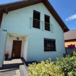 Rodinný dom so sedlovou strechou a vonkajšími žalúziami na oknách.