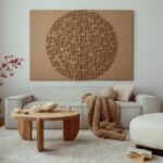 Svetlá menčestrová sedačka s hnedou pletenou dekou a okrúhlym dreveným stolíkom pred veľkou tkanou dekoráciou.