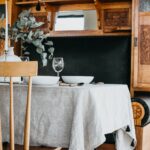 revený jedálenský stôl s hrubým ľanovým obrusom a bielymi taniermi.