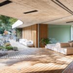 Interiér so svetlými pohovkami a otvorenou presklenou fasádou s priamym prepojením s exteriérom.