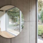 Okrúhle nástenné zrkadlo na betónovom paneli.