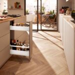 Svetlobéžová kuchynská linka s úzkym bielym výsuvom na fľaše a koreniny.