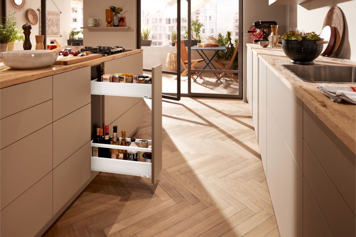 Svetlobéžová kuchynská linka s úzkym bielym výsuvom na fľaše a koreniny.