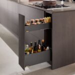 Úzka tmavohnedá kuchynská skrinka s kovovým výsuvom na sklenené fľaše a koreničky v minimalistickom ostrove.